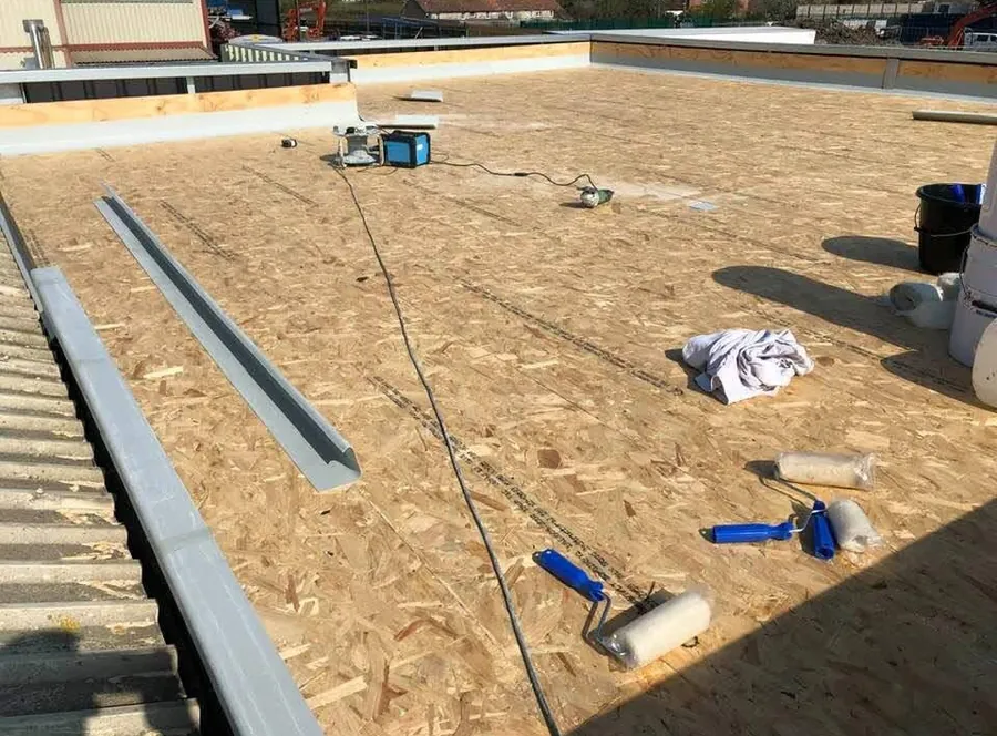 Resin and rollers laid out on a prepared commercial roof deck